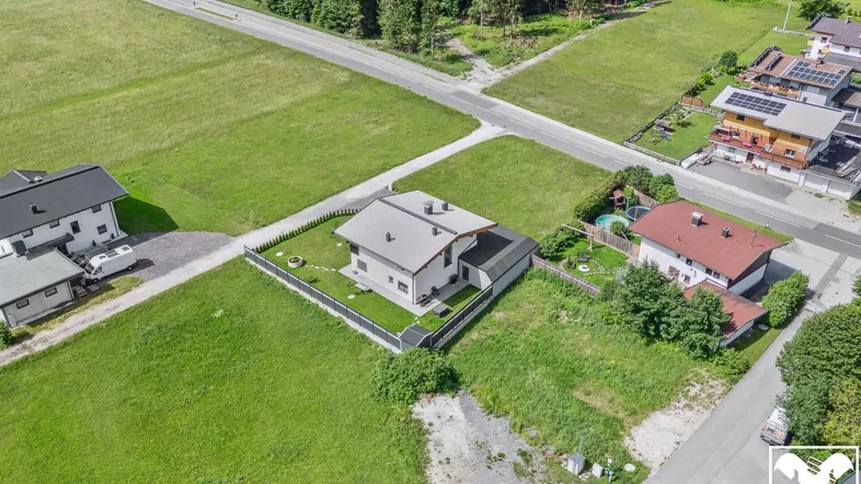 Luftaufnahme eines Einfamilienhauses mit Garten und umliegenden Grünflächen in ländlicher Umgebung.