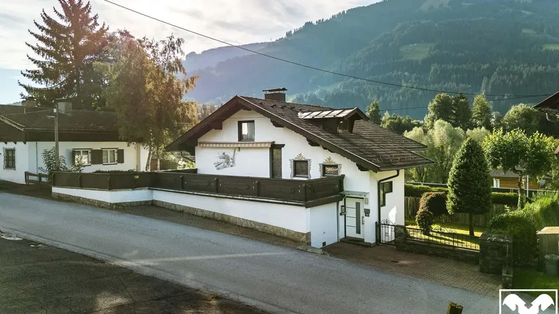Traditionelles Haus mit Satteldach und Bergblick in ländlicher Umgebung.