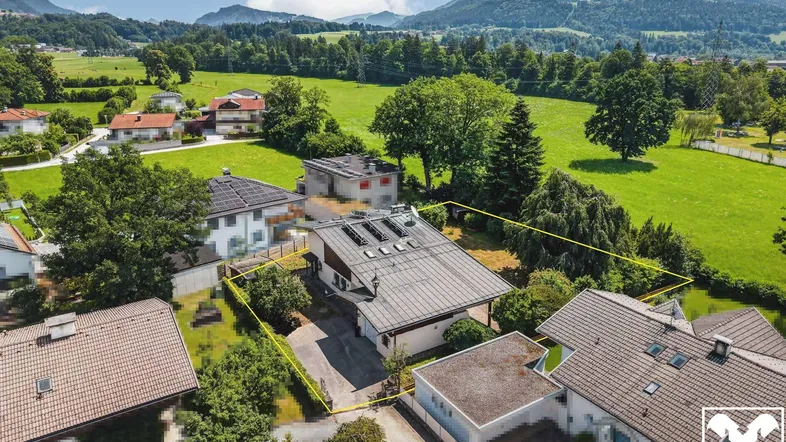 Luftaufnahme des Anwesens mit umliegenden Feldern und Bergen im Hintergrund.