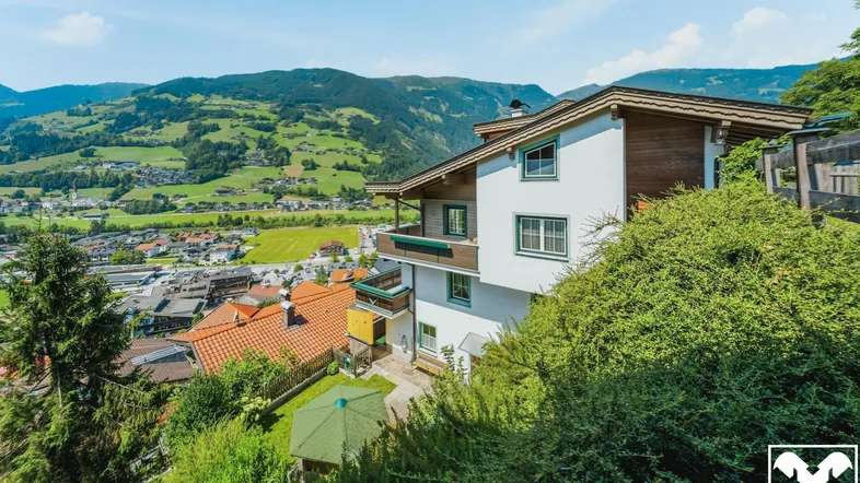 Haus mit mehreren Balkonen und Terrassen in Hanglage mit weitem Blick auf das Tal und die Berge.