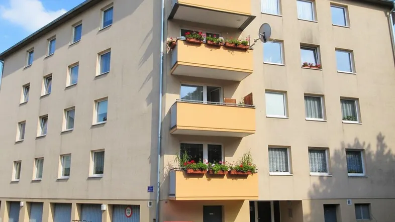 Mehrfamilienhaus mit mehreren Balkonen und Garagen im Erdgeschoss.