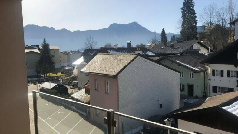 Panoramablick vom Balkon auf die umliegende Wohngegend mit Bergen und einem See im Hintergrund.