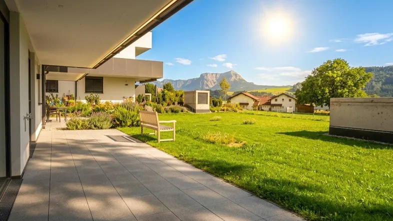 Große geflieste Terrasse mit Rasenfläche und beeindruckendem Bergblick an einem sonnigen Tag.