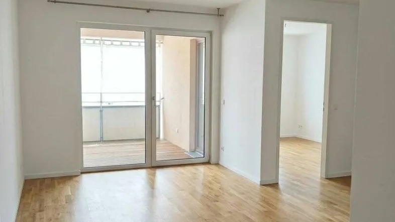Heller Raum mit Parkettboden und Zugang zu einem Balkon, ideal als Wohnzimmer nutzbar.