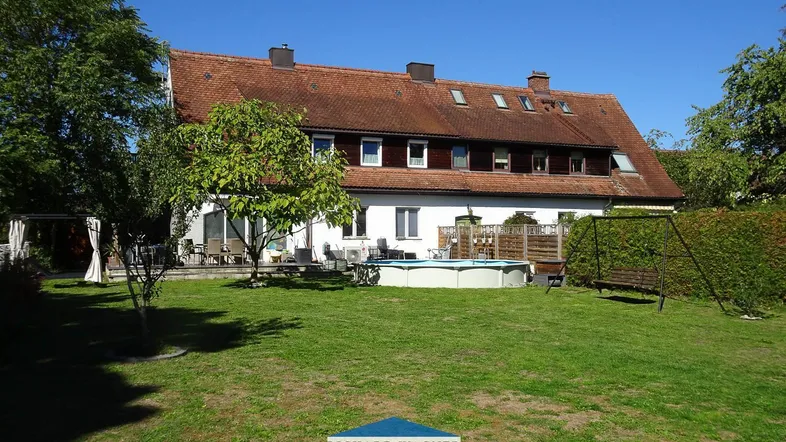 Großer Garten hinter dem Haus mit Rasenfläche, Bäumen und einem Aufstellpool.