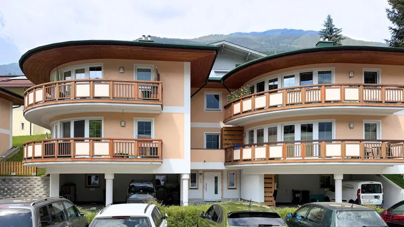 Mehrfamilienhaus mit mehreren Balkonen und Blick auf die umliegende Berglandschaft.