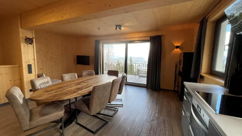 Moderne Küche und Essbereich mit Holztisch und Blick auf die umliegende Landschaft.