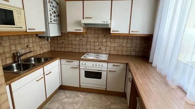 Funktionale Küche mit weißen Schränken, Holz-Arbeitsplatten und Fliesenboden.