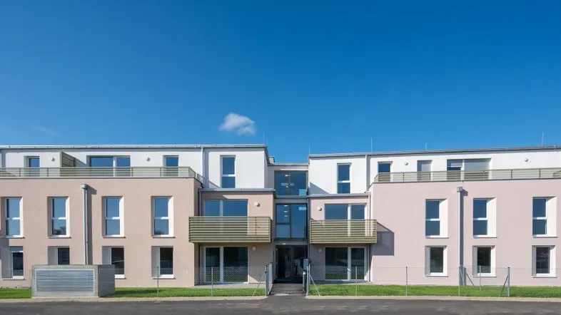 Moderne Wohnanlage mit mehreren Einheiten und Balkonen unter klarem blauem Himmel.