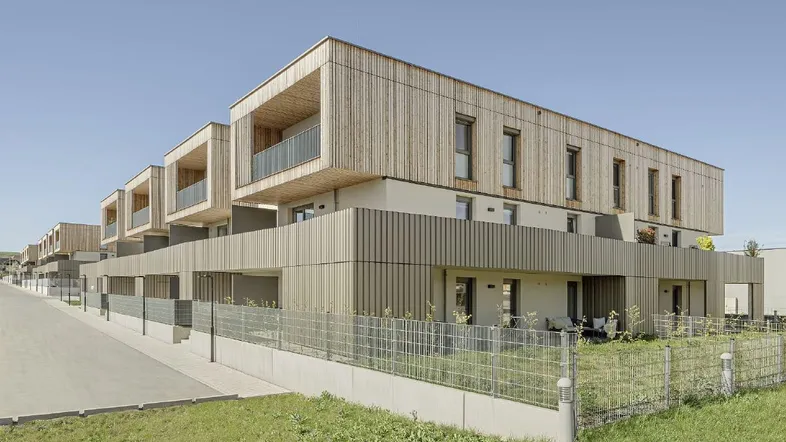 Moderne Wohnanlage mit Holzfassade und Balkonen in einer grünen Umgebung.