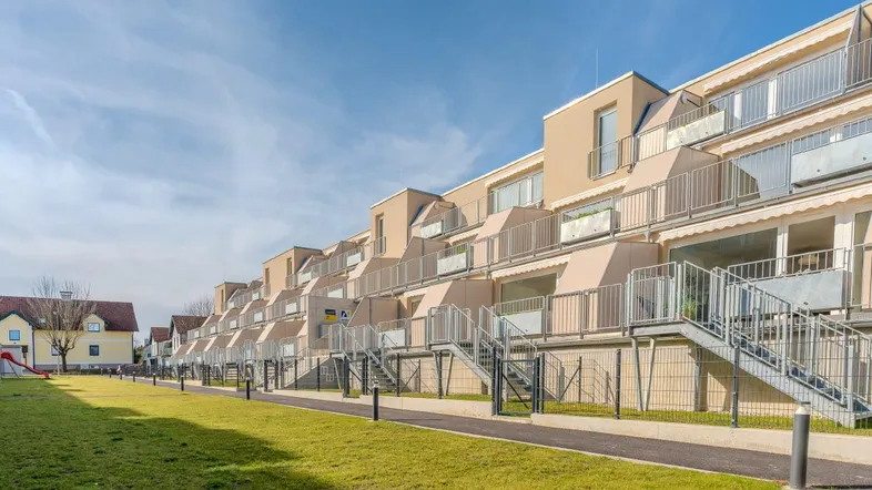 Moderne Wohnanlage mit gestuften Balkonen, Grünflächen und Kinderspielplatz.