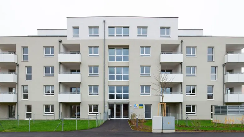 Moderne Wohnanlage mit heller Fassade, vielen Fenstern und Balkonen in einem Neubaugebiet.