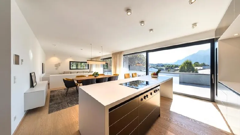 Helle, offene Küche mit Kochinsel und Essbereich, verbunden mit dem Wohnzimmer und Zugang zur Terrasse.
