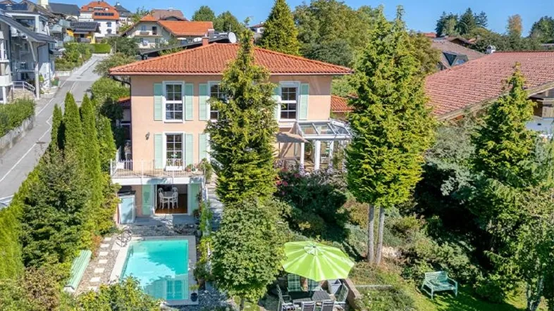 Idyllische Villa mit großem Garten, Pool und Wintergarten, umgeben von viel Grün und Bergblick.
