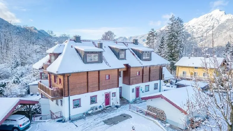 Charmantes Haus im alpinen Stil, umgeben von verschneiter Winterlandschaft und majestätischen Bergen.