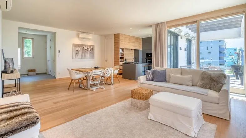 Heller, offener Wohn- und Essbereich mit Holzboden, moderner Küche und Zugang zum Balkon.