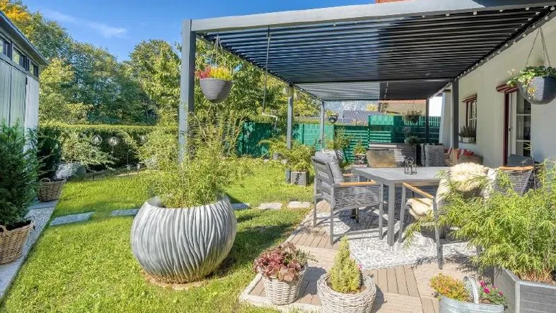 Gemütliche Terrasse mit Pergola, Holzboden und Blick in den gepflegten Garten.