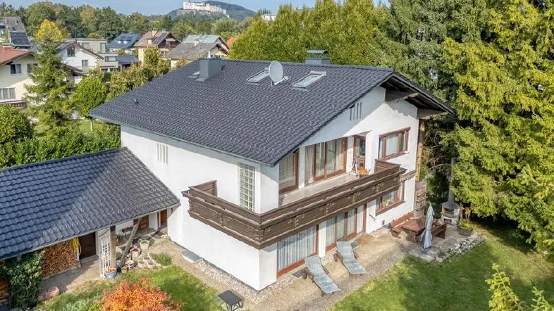 Drohnenaufnahme eines Hauses mit Garten, Balkonen und Blick auf die Festung Hohensalzburg.