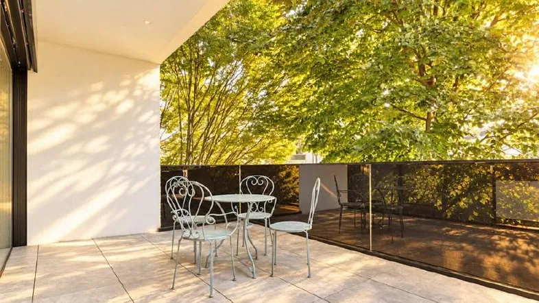 Sonnige Terrasse mit Sitzgelegenheiten und Blick ins Grüne, ideal zum Entspannen im Freien.