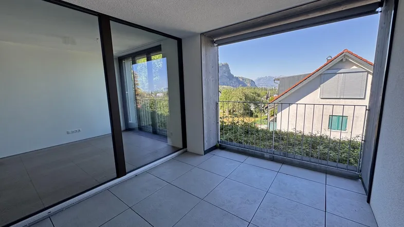 Heller Balkon mit Fliesenboden und weitem Blick auf die umliegende Berglandschaft.