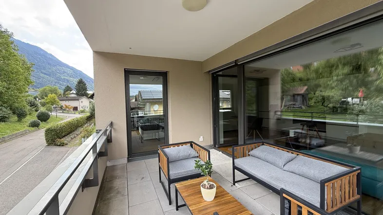Geräumiger Balkon mit modernen Gartenmöbeln und einem schönen Blick auf die umliegenden Berge.