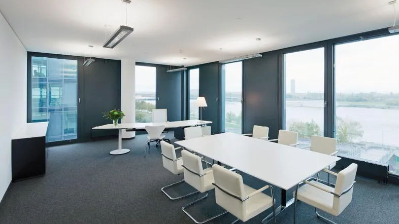Moderner Konferenzraum mit großen Fenstern, die einen weiten Blick auf das Wasser und die Umgebung bieten.