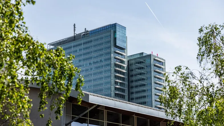 Moderne Hochhäuser mit Glasfassaden und klarem Himmel, umgeben von grünen Bäumen.