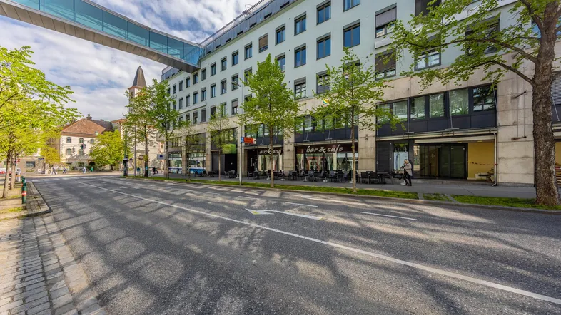 Moderne Gebäudefassade mit großen Fenstern und einem gläsernen Übergang über die Straße.