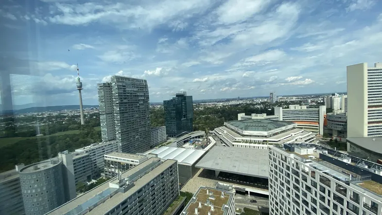 Panoramablick über eine moderne Stadtlandschaft mit Hochhäusern, einem Fluss und weitem Himmel.