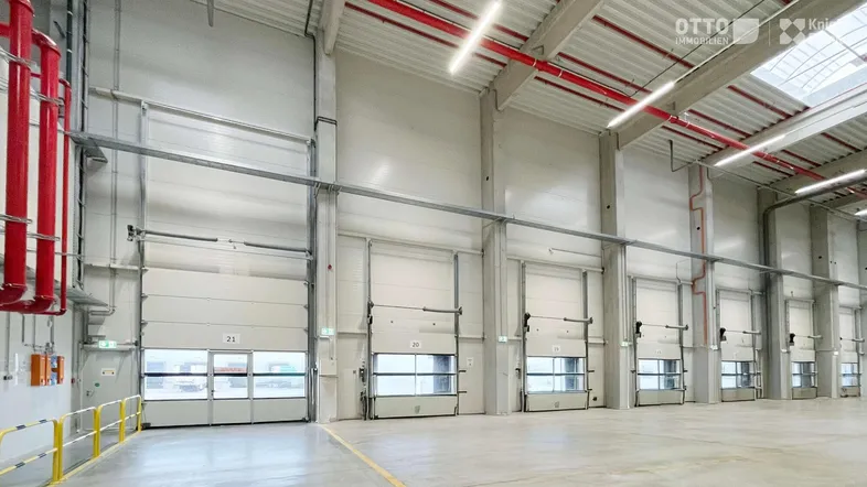 Große Lagerhalle mit mehreren Rolltoren und Laderampen, bereit für den Warenumschlag und Logistikbetrieb.