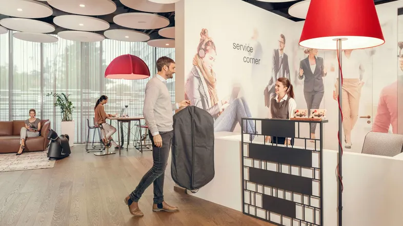 Moderner Empfangsbereich mit Service-Ecke, Sitzgelegenheiten und Holzboden in einem Bürogebäude.