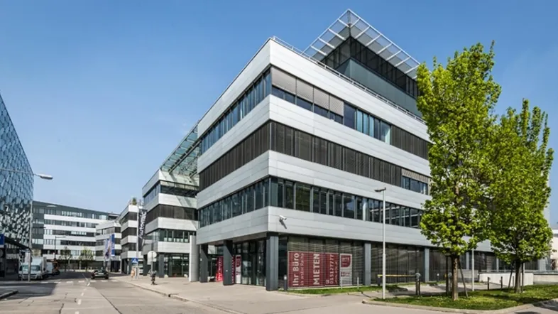 Modernes Bürogebäude mit Glasfassade und klaren Linien unter blauem Himmel.