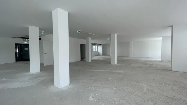 Großer, leerer Büroraum mit Säulen und Betonboden, bereit für den Ausbau und die individuelle Gestaltung.