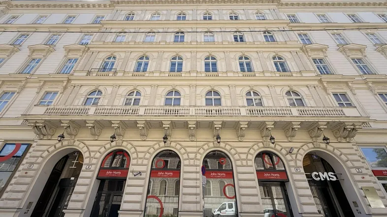 Elegante historische Fassade eines mehrstöckigen Gebäudes mit vielen Fenstern und Geschäftsräumen im Erdgeschoss.