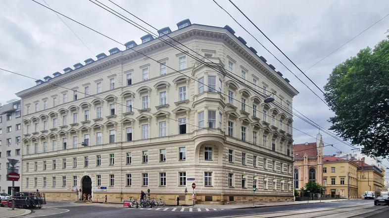 Historisches Eckgebäude mit klassischer Architektur und vielen Fenstern in städtischer Umgebung.