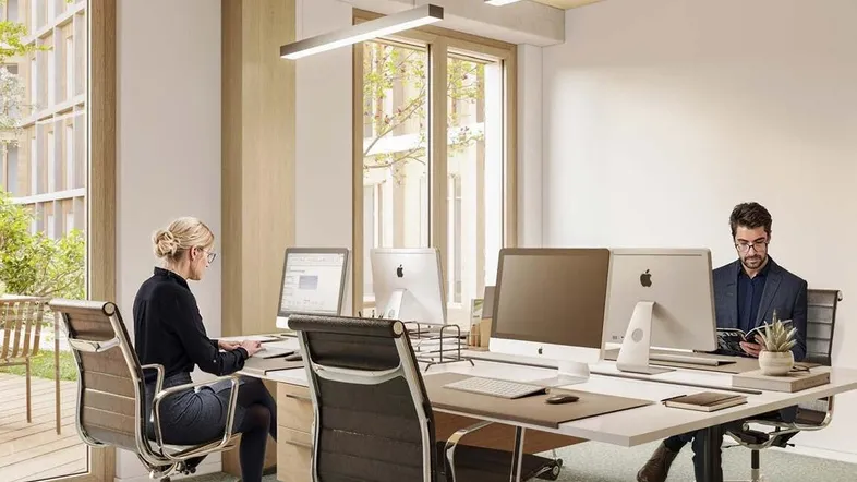 Modernes Büro mit mehreren Arbeitsplätzen, großen Fenstern und Blick auf den begrünten Innenhof.