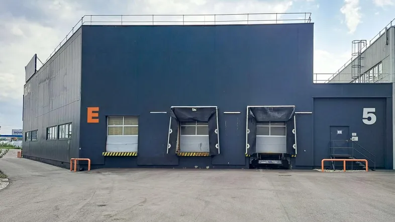 Außenansicht eines modernen Industriegebäudes mit mehreren Laderampen und dunkler Fassade.