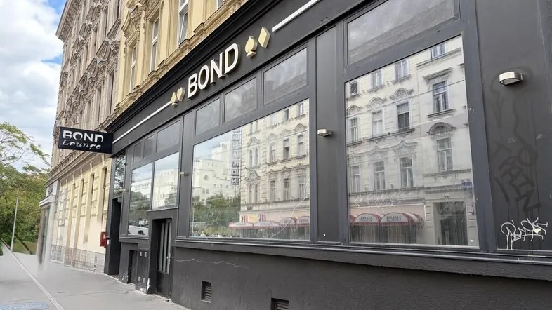 Fassade eines Geschäftsgebäudes mit großen Fenstern und dem Schriftzug "BOND" in einer städtischen Umgebung.