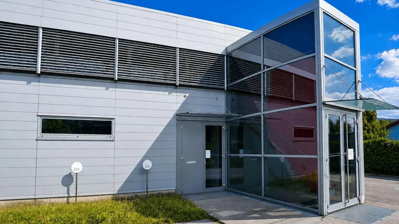 Moderne Gewerbeimmobilie mit Glasfassade am Eingangsbereich und gepflegter Außenanlage.