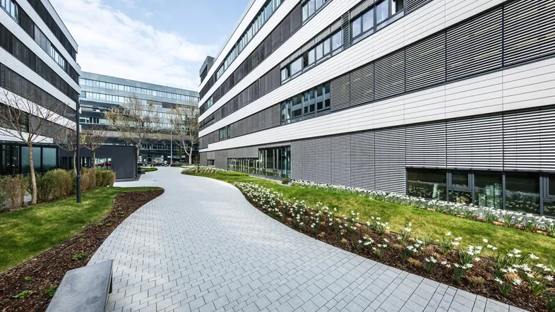 Moderner Bürokomplex mit gepflastertem Weg, Grünflächen und zeitgenössischer Architektur.