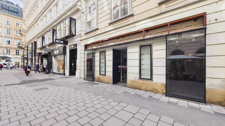 Blick auf eine belebte Einkaufsstraße mit historischen Gebäuden und Geschäften in der Stadt.