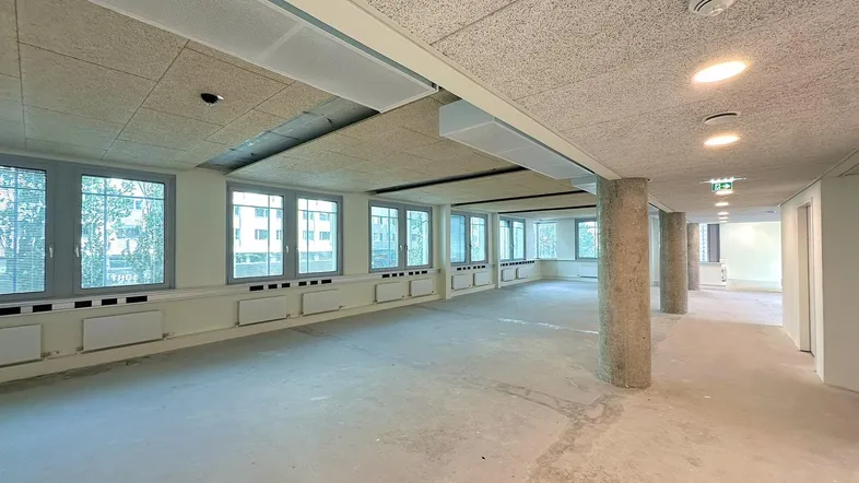 Großer, heller Innenraum mit vielen Fenstern und sichtbaren Säulen, bereit für den Ausbau.