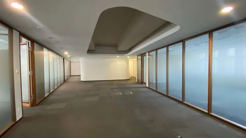 Geräumiger Büroflur mit Teppichboden, Glaswänden und moderner Deckenbeleuchtung, ideal für ein dynamisches Arbeitsumfeld.