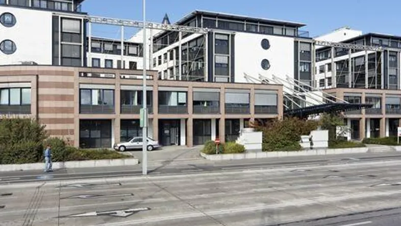 Modernes Bürogebäude mit mehreren Etagen, großen Fenstern und einer Mischfassade aus Putz und Klinker.