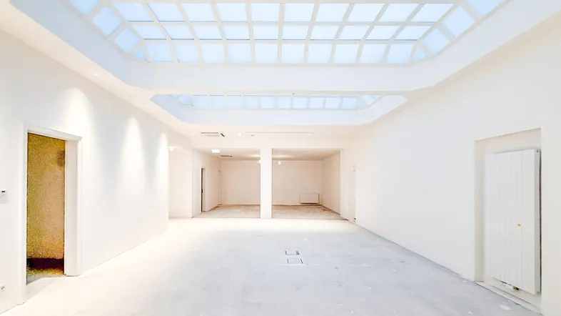 Großer, heller Innenraum mit Oberlichtern und weißen Wänden, bereit für den Ausbau und die individuelle Gestaltung.