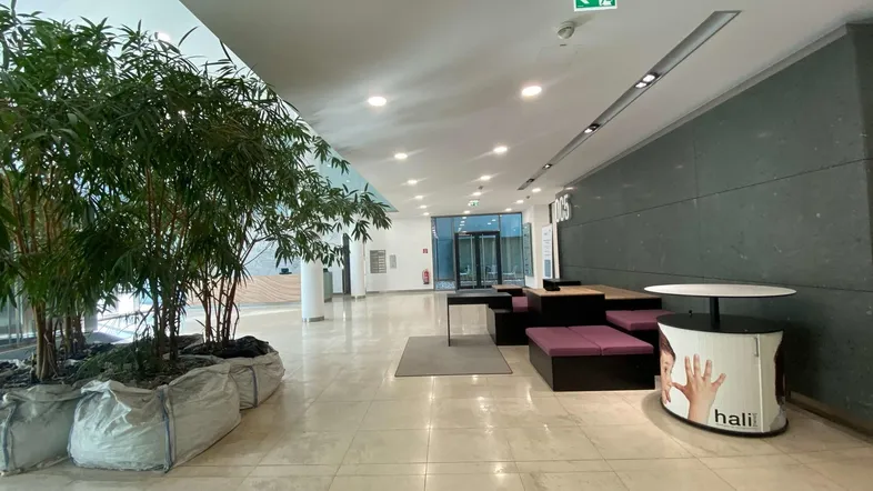 Geräumige und moderne Lobby mit Sitzgelegenheiten, Pflanzen und hellem Fliesenboden, die einen einladenden Eingangsbereich bietet.