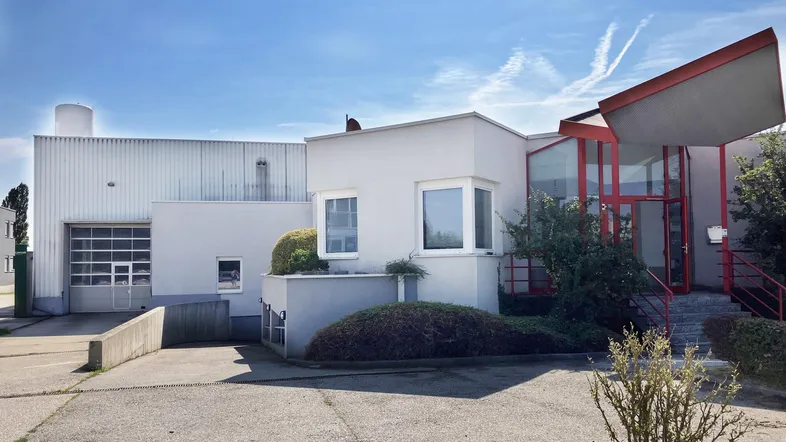 Außenansicht eines modernen Gewerbegebäudes mit großer Garageneinfahrt und separatem Eingangsbereich.