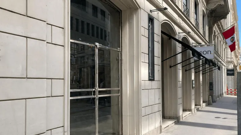 Moderne Geschäftsfassade mit großen Glasfenstern und heller Steinverkleidung, die eine einladende Straßenansicht bietet.