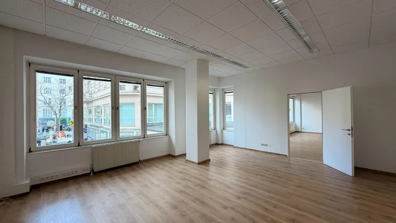 Geräumiges Büro mit hellem Laminatboden, großen Fenstern und Blick auf die umliegende Stadt.