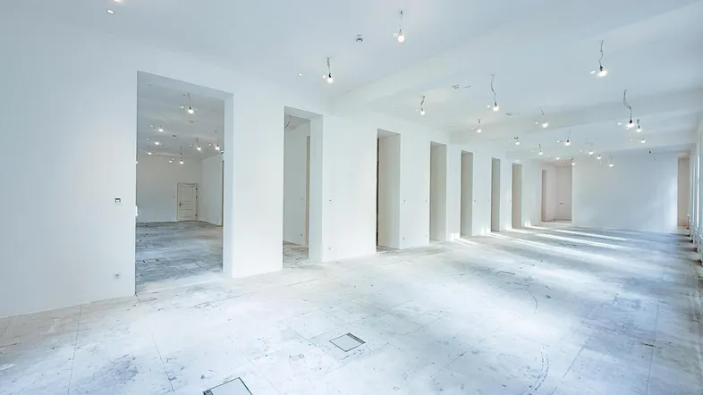 Großer, heller Gewerberaum mit vielen Türöffnungen und unfertigem Boden, bereit für den Ausbau.